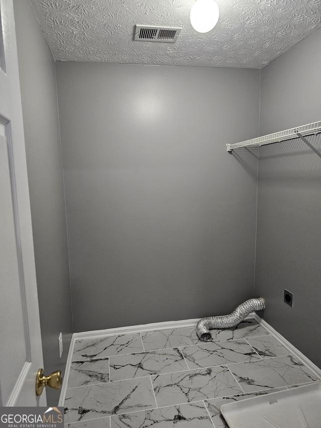 laundry room featuring hookup for an electric dryer and a textured ceiling