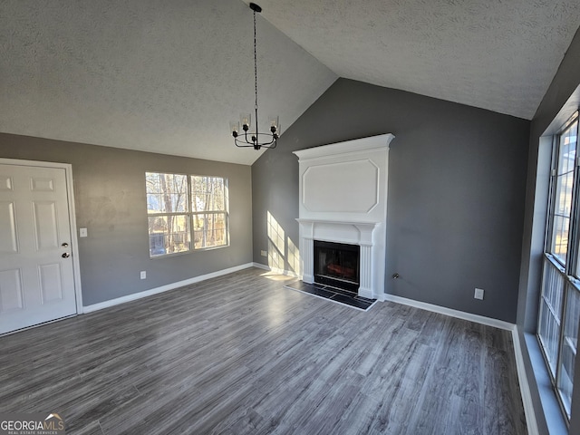 unfurnished living room with dark hardwood / wood-style flooring, a textured ceiling, lofted ceiling, and a chandelier