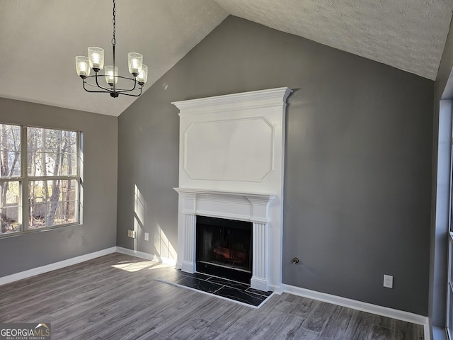 unfurnished living room with dark wood-type flooring, vaulted ceiling, a tile fireplace, and a notable chandelier