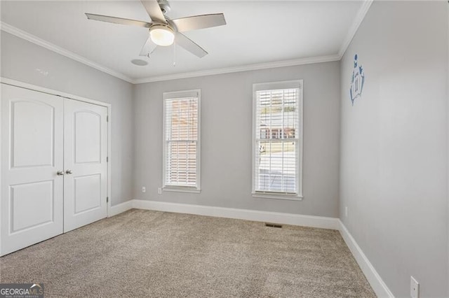 unfurnished bedroom with light carpet, crown molding, a closet, and ceiling fan