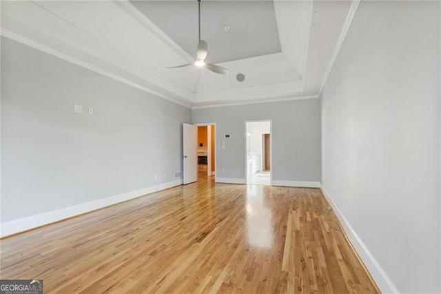 spare room with a tray ceiling, crown molding, ceiling fan, and light wood-type flooring