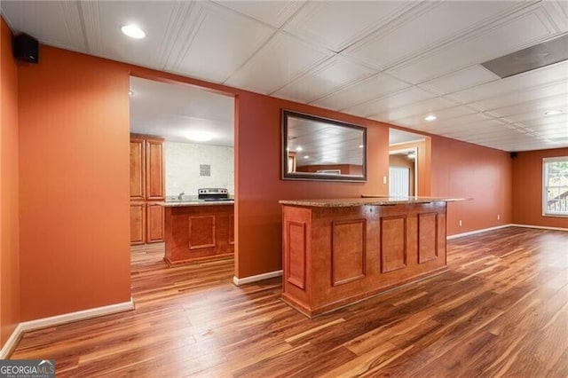 bar with light stone countertops and hardwood / wood-style floors