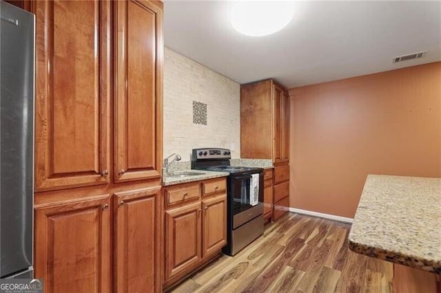 kitchen featuring stainless steel appliances, light stone countertops, dark wood-type flooring, and sink