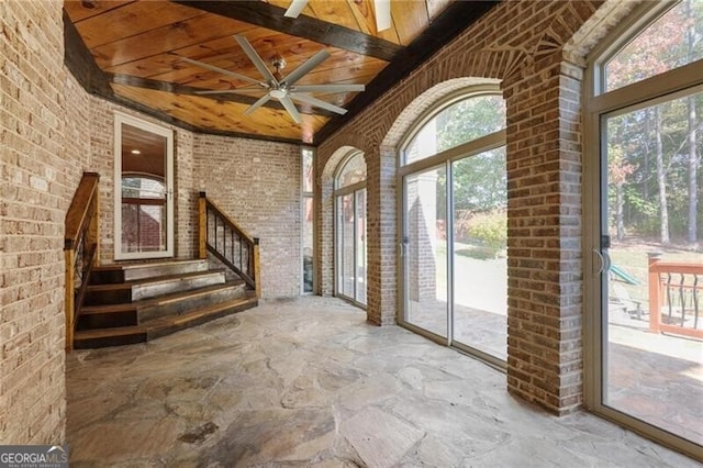 interior space with wooden ceiling, ceiling fan, and brick wall