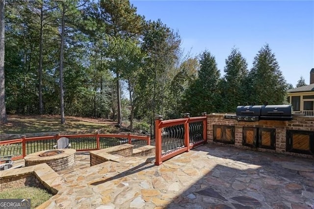 view of patio featuring area for grilling, a grill, and a fire pit