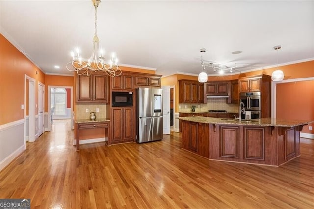 kitchen with light stone counters, hanging light fixtures, hardwood / wood-style floors, and appliances with stainless steel finishes