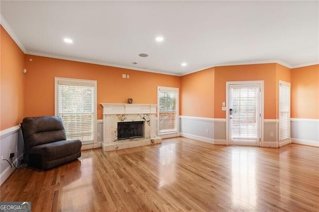 living room featuring crown molding, a healthy amount of sunlight, and light wood-type flooring