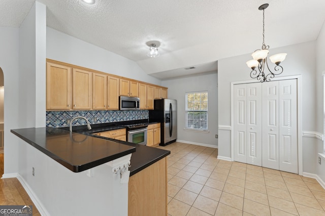 kitchen featuring lofted ceiling, hanging light fixtures, appliances with stainless steel finishes, kitchen peninsula, and backsplash