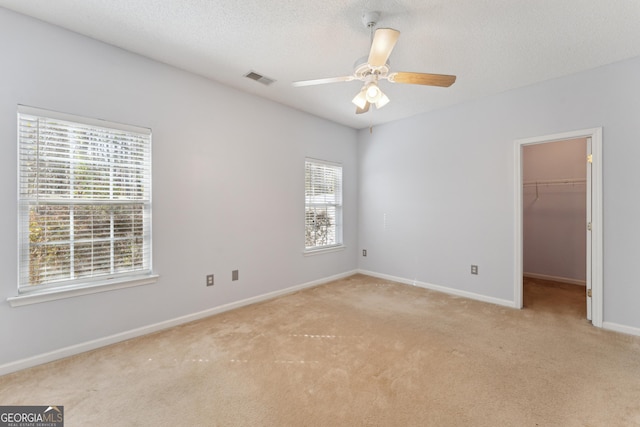 spare room with ceiling fan, light colored carpet, and a textured ceiling