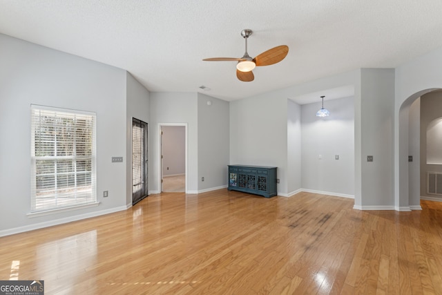 unfurnished living room with ceiling fan, a textured ceiling, and light wood-type flooring