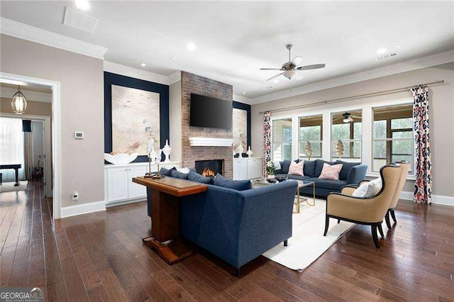 living room featuring a brick fireplace, crown molding, dark hardwood / wood-style floors, and ceiling fan