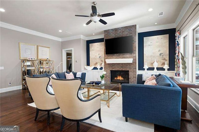 living room with a fireplace, ornamental molding, dark hardwood / wood-style floors, and ceiling fan