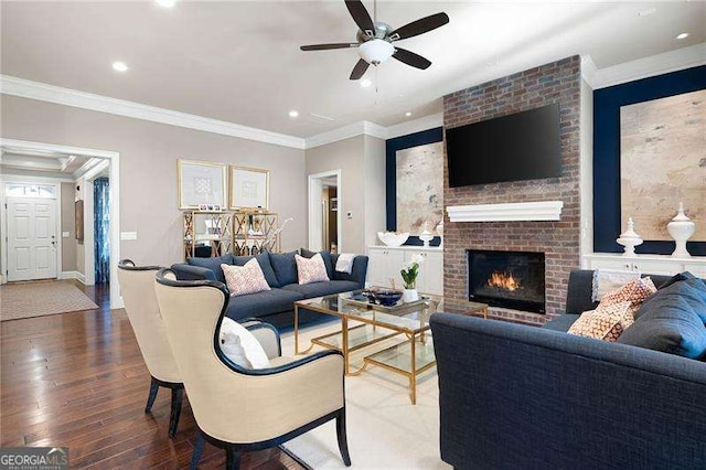 living room with crown molding, ceiling fan, a fireplace, and hardwood / wood-style flooring