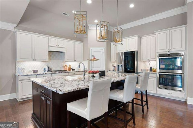 kitchen with white cabinetry and an island with sink