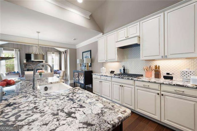 kitchen with stainless steel gas stovetop, sink, white cabinets, and decorative light fixtures