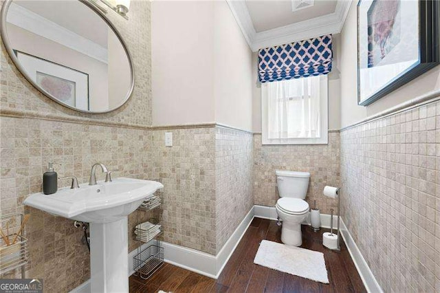 bathroom with hardwood / wood-style flooring, crown molding, and toilet