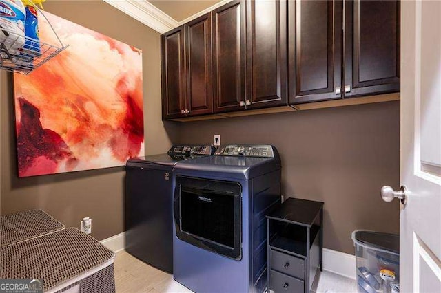 laundry area featuring cabinets, ornamental molding, and washer and clothes dryer