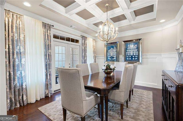 dining space with dark hardwood / wood-style flooring, ornamental molding, coffered ceiling, an inviting chandelier, and french doors