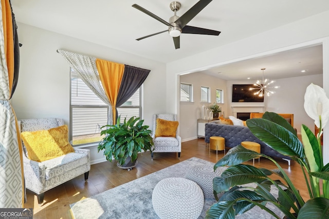 sitting room with dark hardwood / wood-style flooring and ceiling fan with notable chandelier