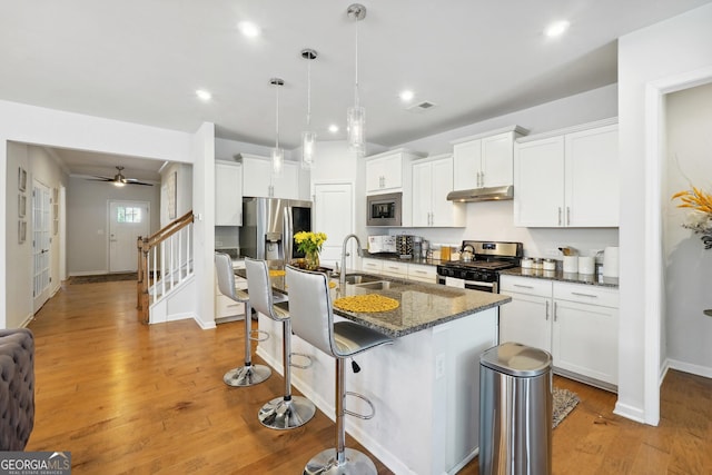 kitchen with an island with sink, appliances with stainless steel finishes, sink, and white cabinets