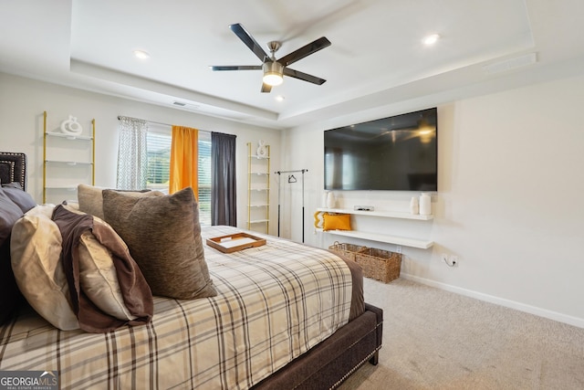 carpeted bedroom featuring ceiling fan and a raised ceiling