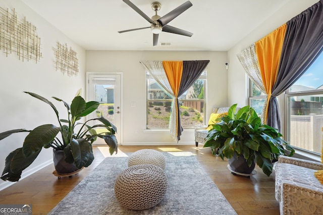 living area featuring wood-type flooring, plenty of natural light, and ceiling fan