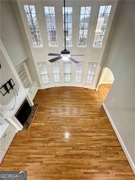 unfurnished living room with hardwood / wood-style flooring, ceiling fan, and a high ceiling