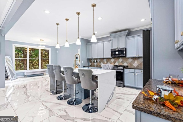 kitchen featuring pendant lighting, dark stone countertops, backsplash, stainless steel appliances, and a center island with sink