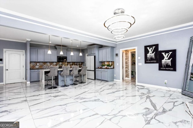 kitchen with a breakfast bar, decorative light fixtures, an island with sink, gray cabinetry, and white fridge