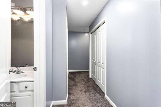 corridor with sink and dark carpet