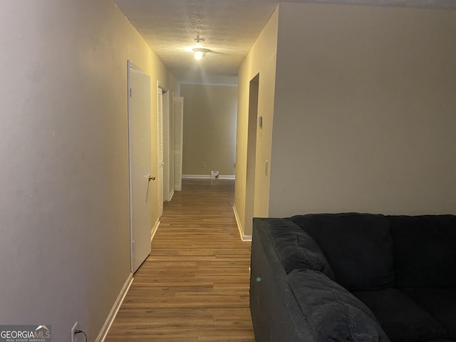 corridor featuring a textured ceiling and light hardwood / wood-style flooring