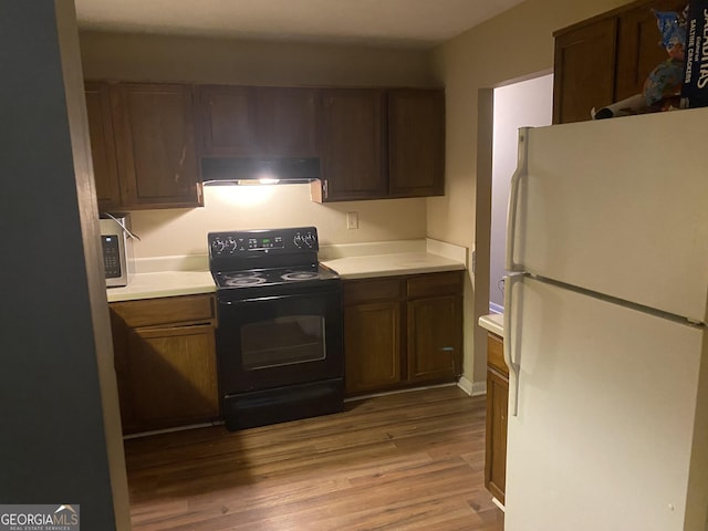 kitchen with black range with electric cooktop, light hardwood / wood-style floors, and white fridge