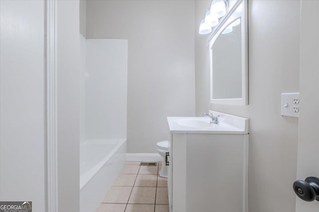 bathroom featuring vanity, a tub to relax in, tile patterned flooring, and toilet