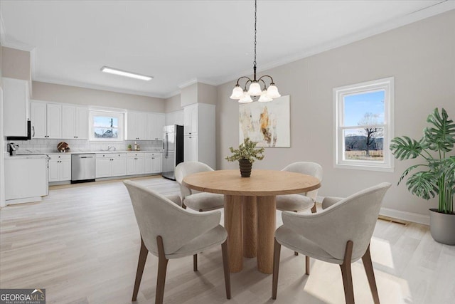 dining room with plenty of natural light, ornamental molding, a chandelier, and light wood-type flooring