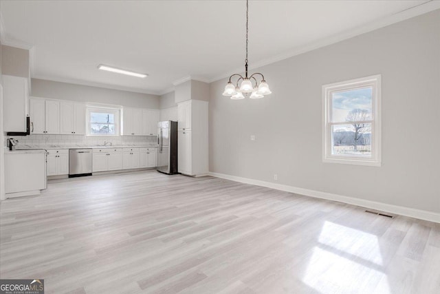 kitchen featuring appliances with stainless steel finishes, pendant lighting, tasteful backsplash, white cabinetry, and crown molding