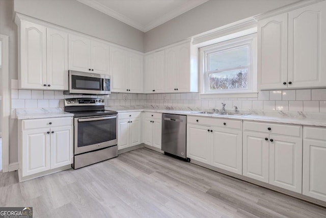 kitchen featuring appliances with stainless steel finishes, sink, white cabinets, decorative backsplash, and crown molding