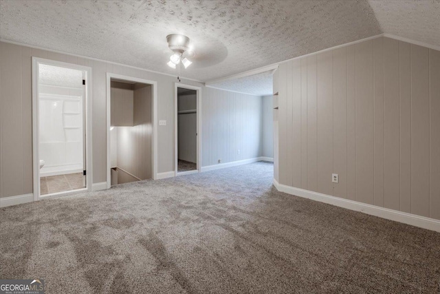 unfurnished bedroom with vaulted ceiling, carpet, ensuite bathroom, and a textured ceiling