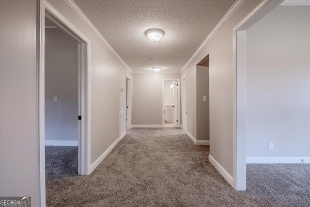 hallway with ornamental molding, carpet, and a textured ceiling