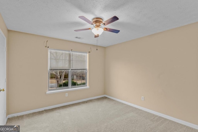 empty room featuring ceiling fan, light colored carpet, and a textured ceiling