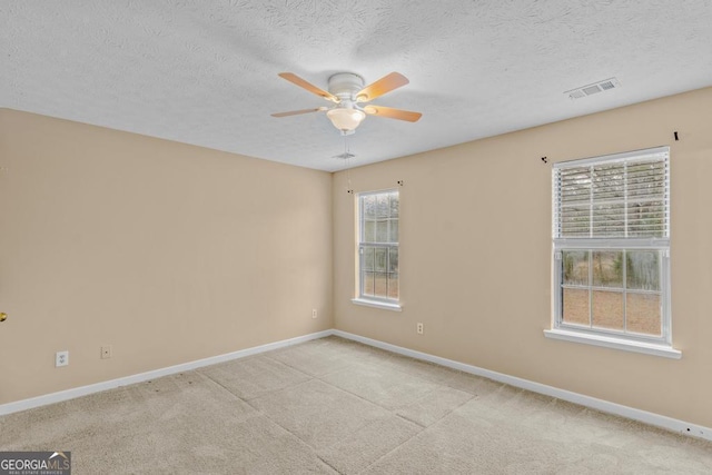 unfurnished room featuring ceiling fan, light carpet, and a textured ceiling