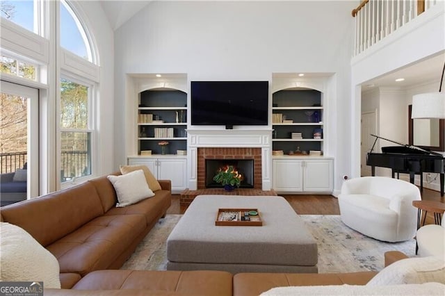 living room with high vaulted ceiling, a fireplace, built in features, and light wood-type flooring