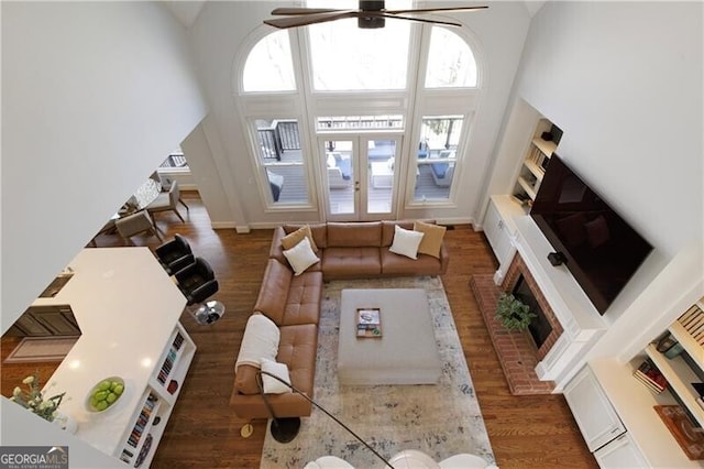 living room with ceiling fan, a towering ceiling, dark hardwood / wood-style flooring, and french doors