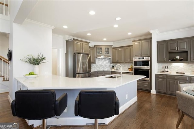 kitchen featuring dark wood-type flooring, sink, a breakfast bar area, kitchen peninsula, and stainless steel appliances