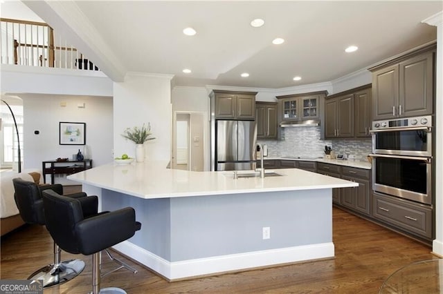 kitchen with stainless steel appliances, ornamental molding, backsplash, and dark hardwood / wood-style flooring