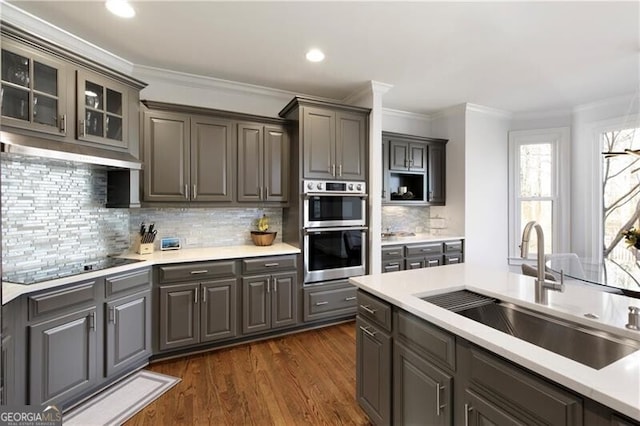 kitchen featuring sink, black electric cooktop, ornamental molding, dark hardwood / wood-style flooring, and stainless steel double oven