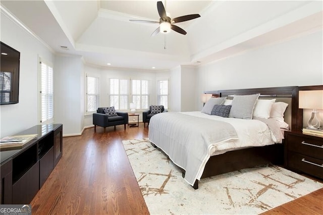 bedroom featuring crown molding, hardwood / wood-style floors, and a tray ceiling