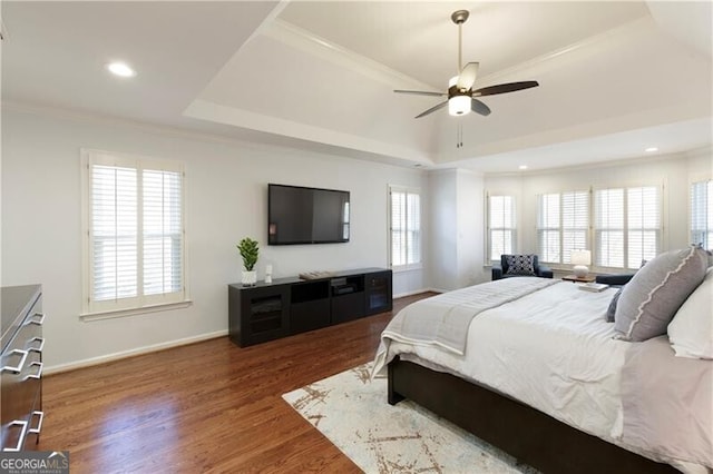 bedroom featuring dark wood-type flooring, ceiling fan, ornamental molding, and a raised ceiling