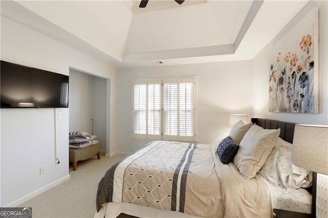 carpeted bedroom with ceiling fan and a tray ceiling