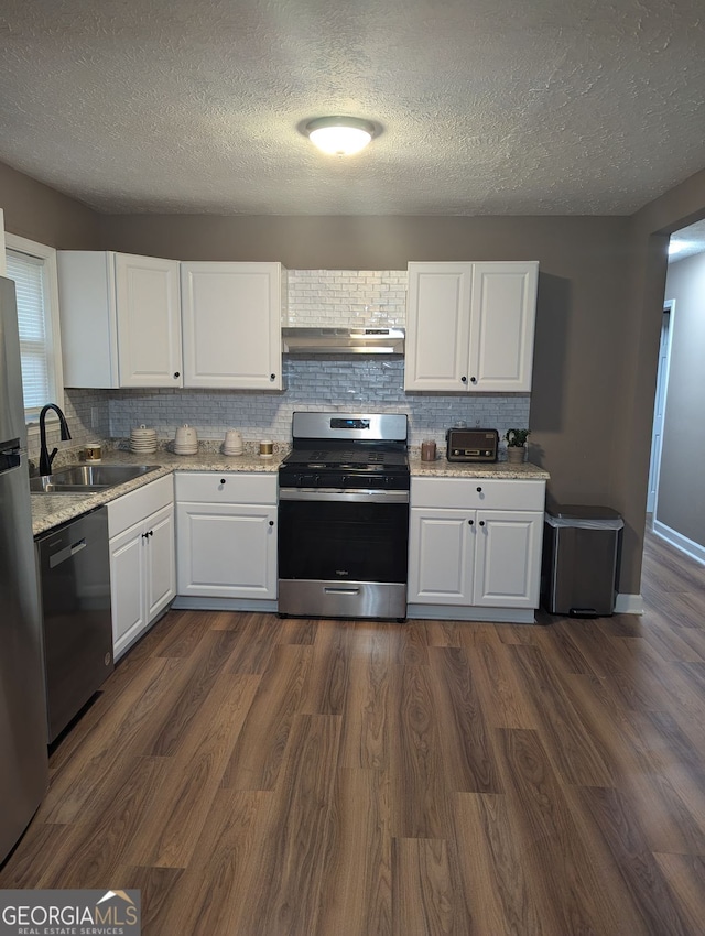 kitchen featuring dark wood-type flooring, sink, appliances with stainless steel finishes, white cabinets, and backsplash