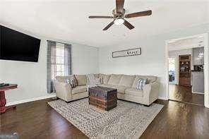 living room with dark hardwood / wood-style flooring and ceiling fan